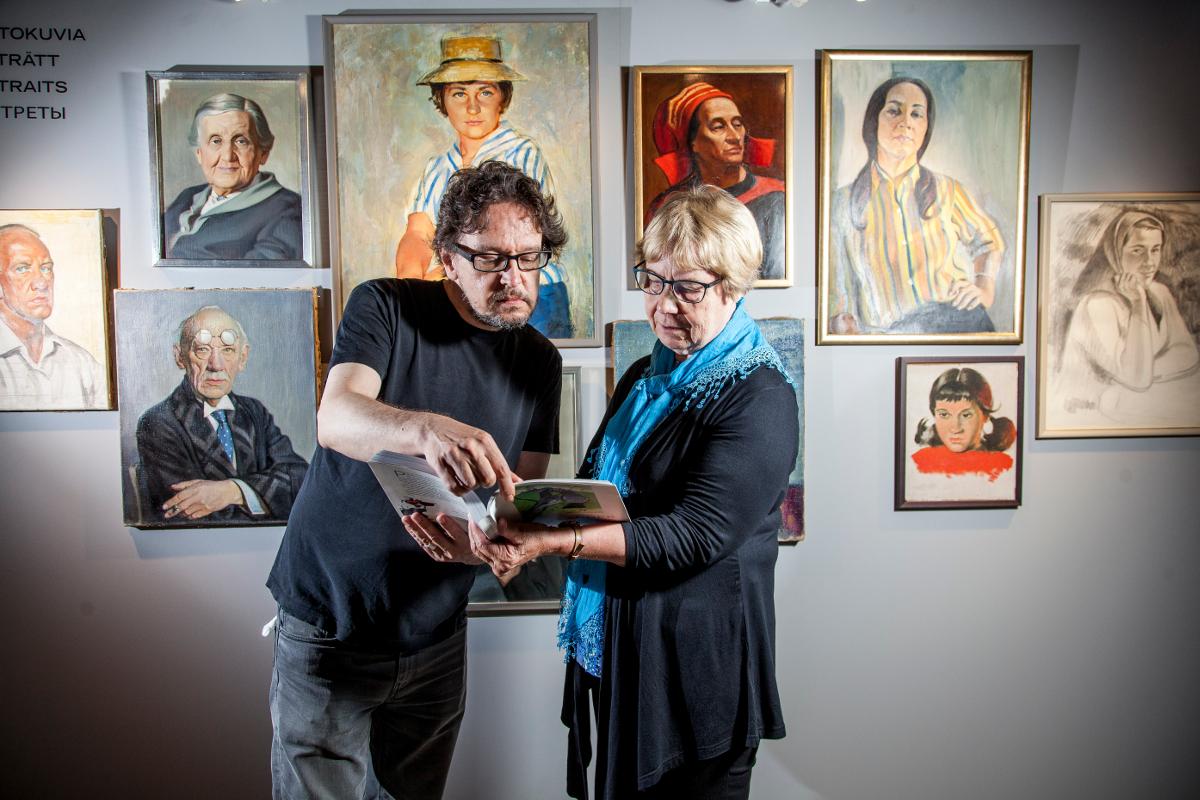 Sisko Ylimartimo esittelee Aleksander Lindebergistä tekemäänsä kirjaa taiteilijan sukulaiselle Anton Nikkilälle Helsingin tuomiokirkon kryptan näyttelyssä.